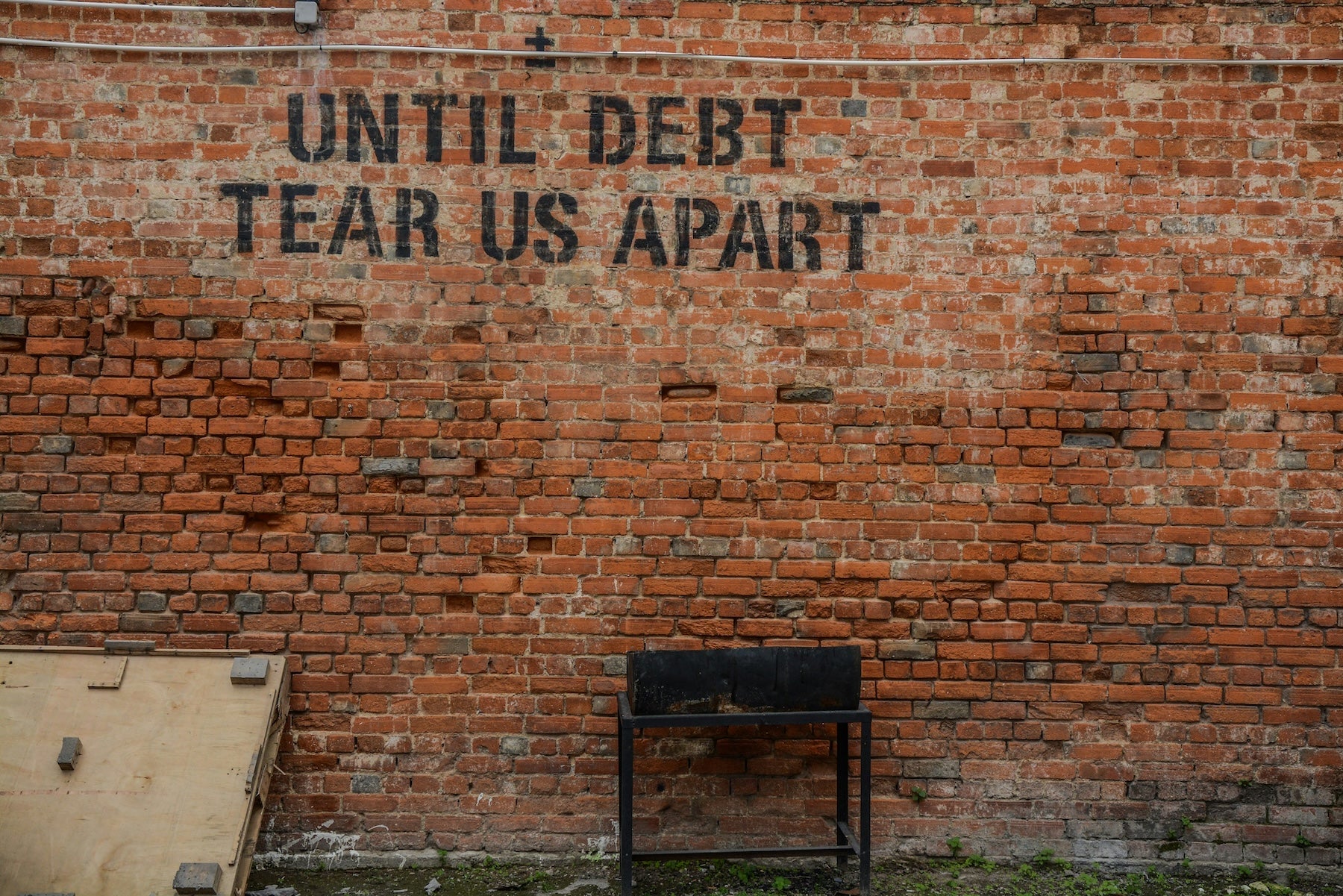 Until Debt tear us apart written on a Brick wall for an Empower yourself financially blog post