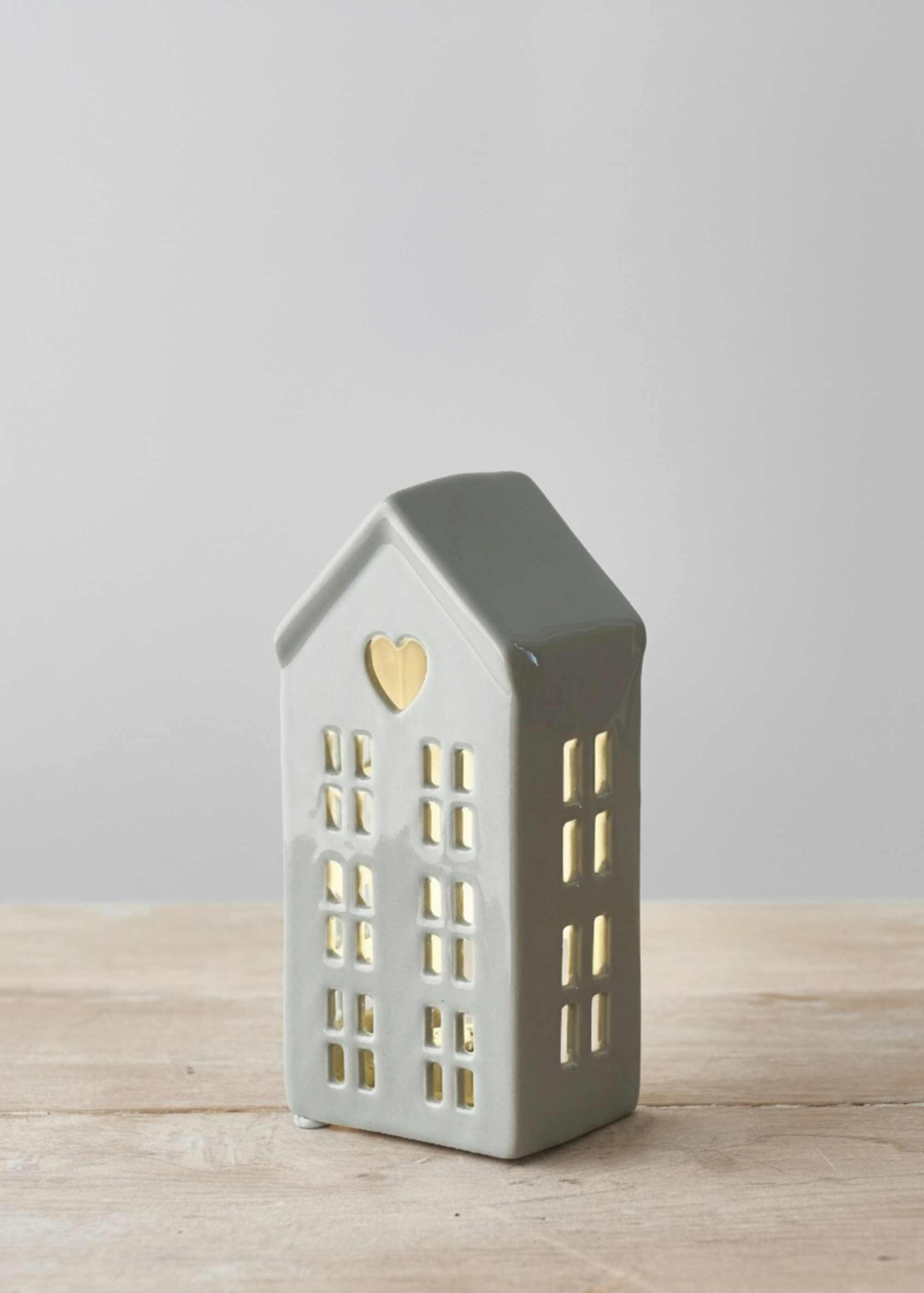 Truly Lifestyle house-shaped lantern with a heart detail on a wooden surface and light gray background