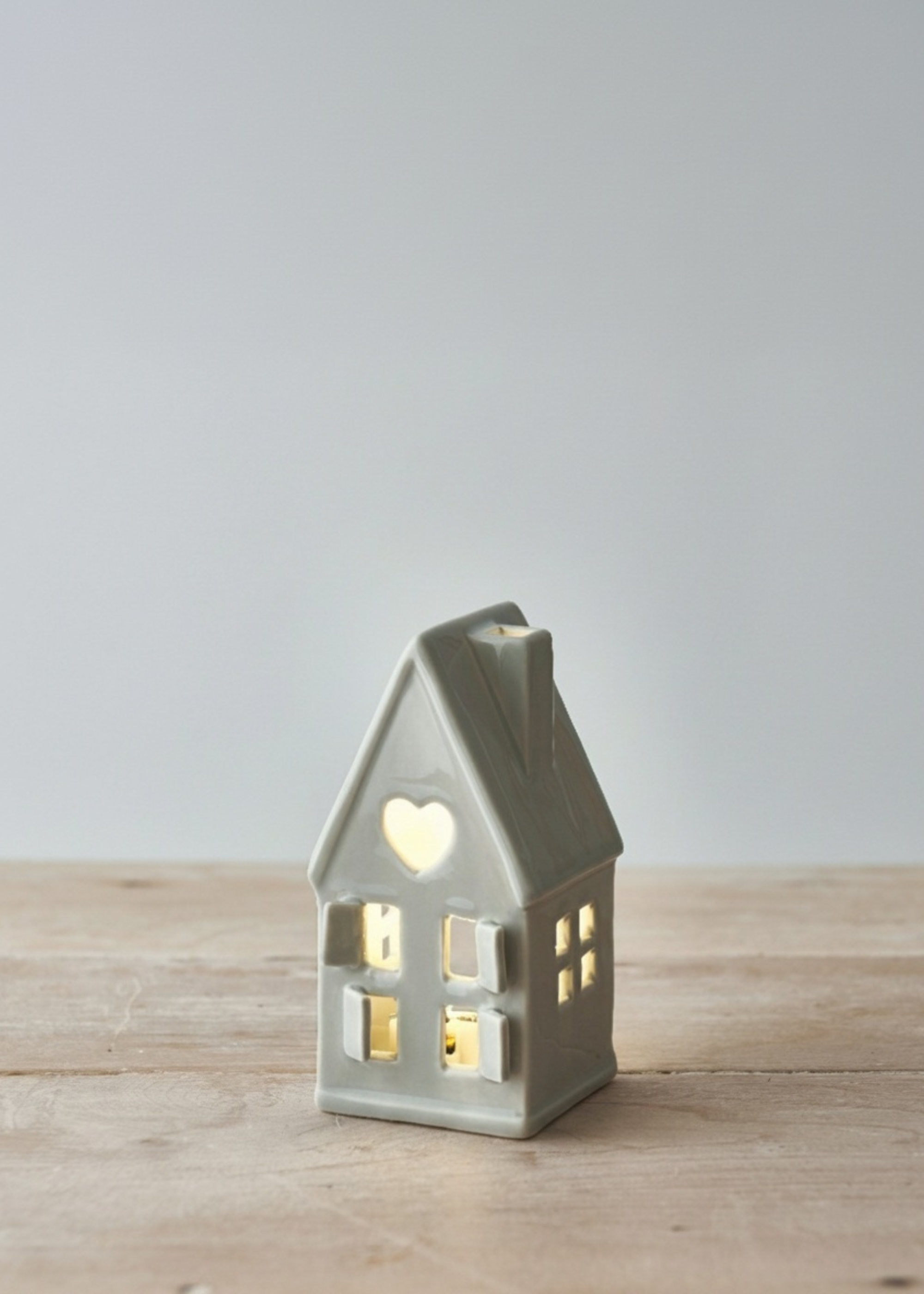 Truly Lifestyle Grey Ceramic house-shaped lantern with a heart window on a wooden surface