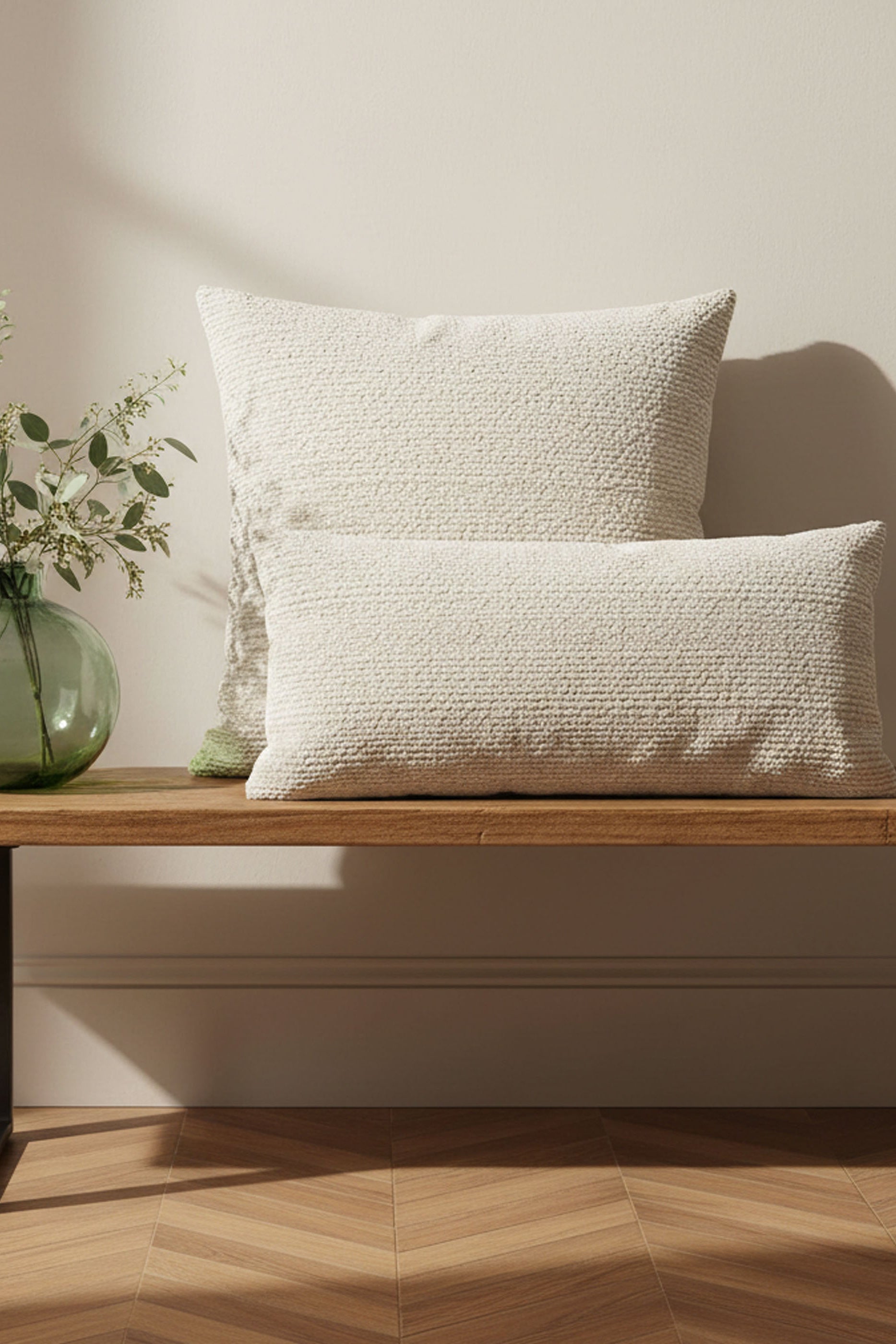 Two textured pillows on a wooden bench with a neutral background