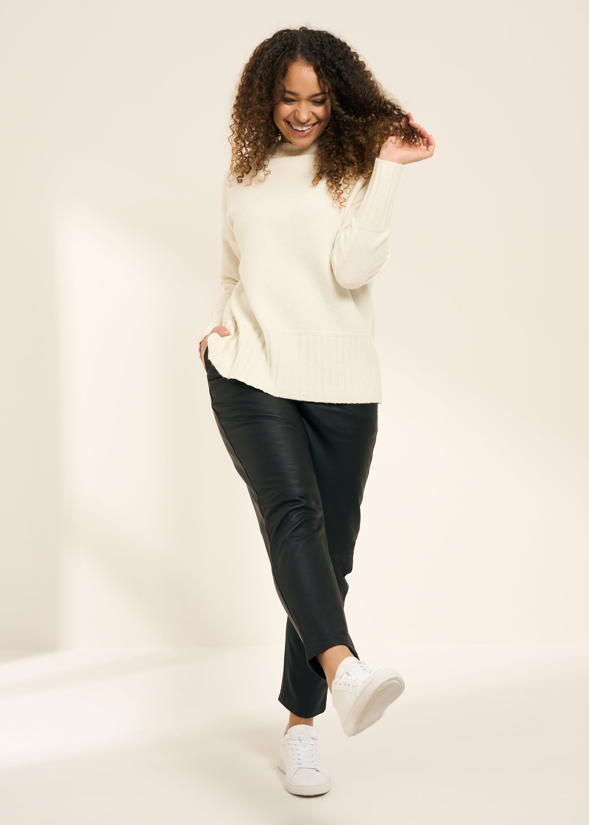 TRULY LIFESTYLE WOMENS WHITE FUNNEL NECK JUMPER WITH RIBBED HEM ON MODEL WITH LEATHER TROUSERS