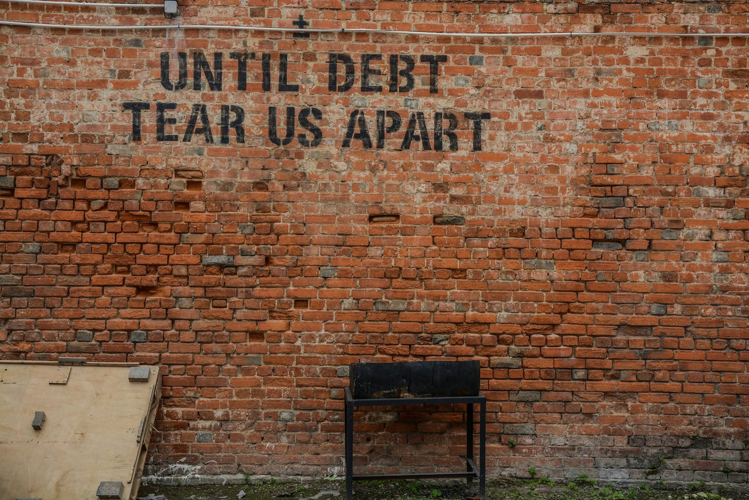 Until Debt tear us apart written on a Brick wall for an Empower yourself financially blog post