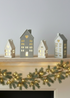 Truly Lifestyle Set of small house-shaped lanterns on a mantelpiece with a Christmas garland.