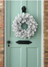 TRULY LIFESTYLE SNOW COVERED WREATH HANGING ON A BLUE DOOR