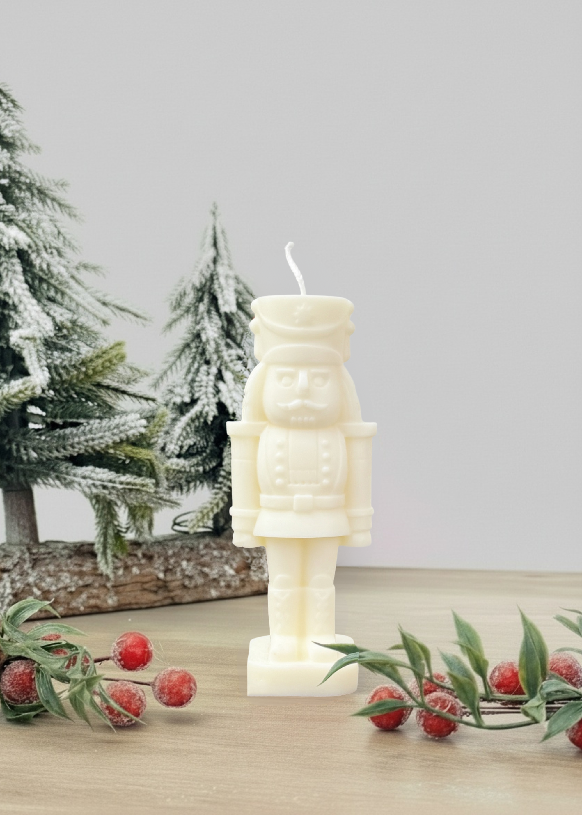 Truly Lifestyle White nutcracker-shaped candle on a wooden surface with Christmas decorations in the background.