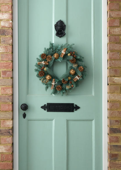 TRULY LIFESTYLE CHRISTMAS WREATH WITH DRIED CINNAMON, ACORNS, ORANGES AND BRONZE BELLS ON GREEN DOOR