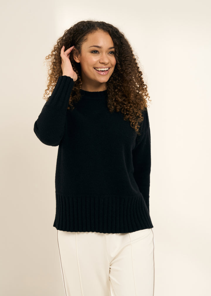 TRULY LIFESTYLE WOMENS BLACK FUNNEL NECK JUMPER WITH RIBBED HEM DETAILING ON  MODEL WITH CREAM WIDE LEGGED TROUSERS