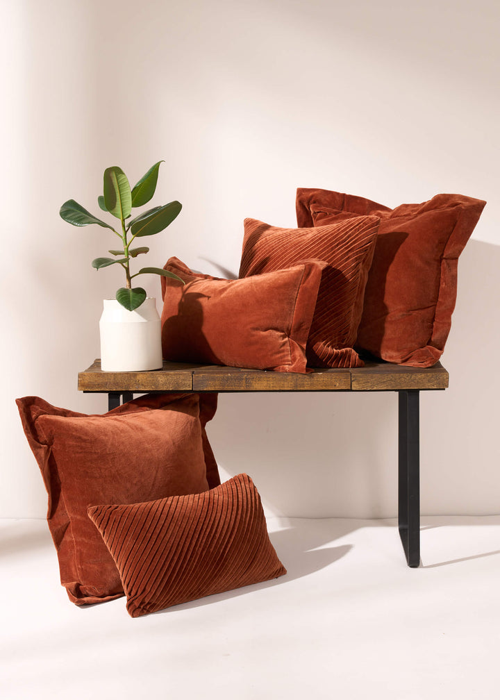 TRULY LIFESTYLE COLLECTION IMAGE WITH ALL BURNT ORANGE VELVET CUSHIONS ON A BENCH WITH A FLOWER