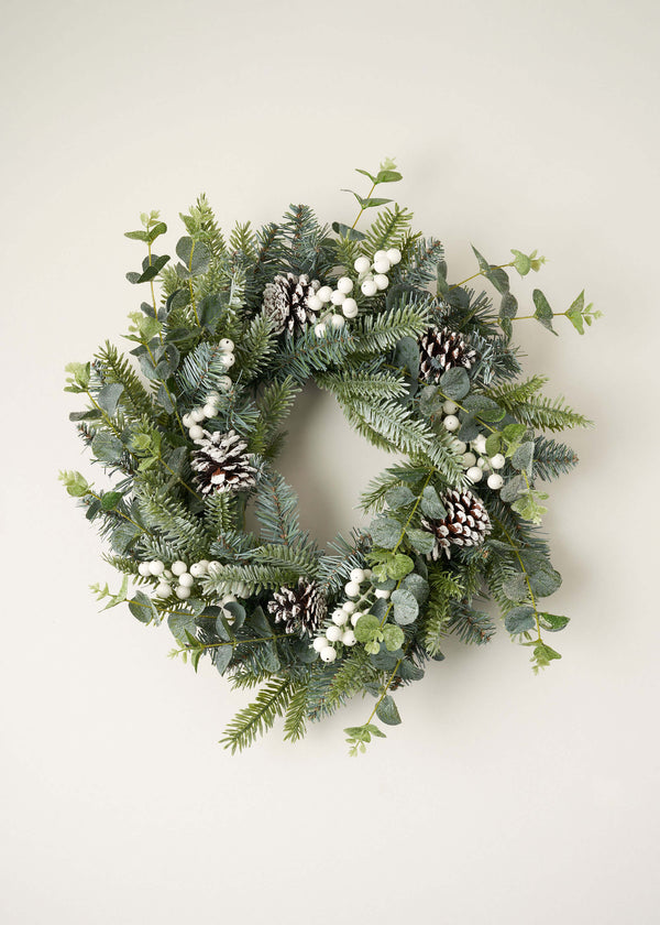 Green Christmas Wreath With White Berries and Pine Cones Hanging Up | Truly Lifestyle