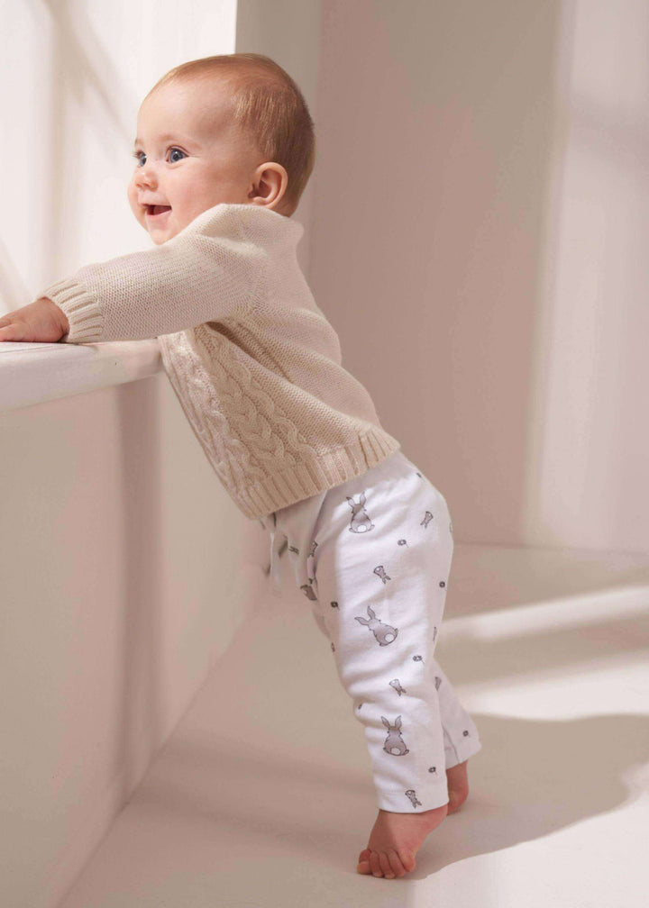 Baby Cream Cable Knit Jumper On Baby With Bunny Print Leggings Standing Up | Truly Lifestyle